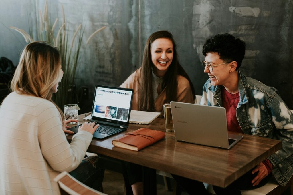 Three women sitting at a table with laptops.