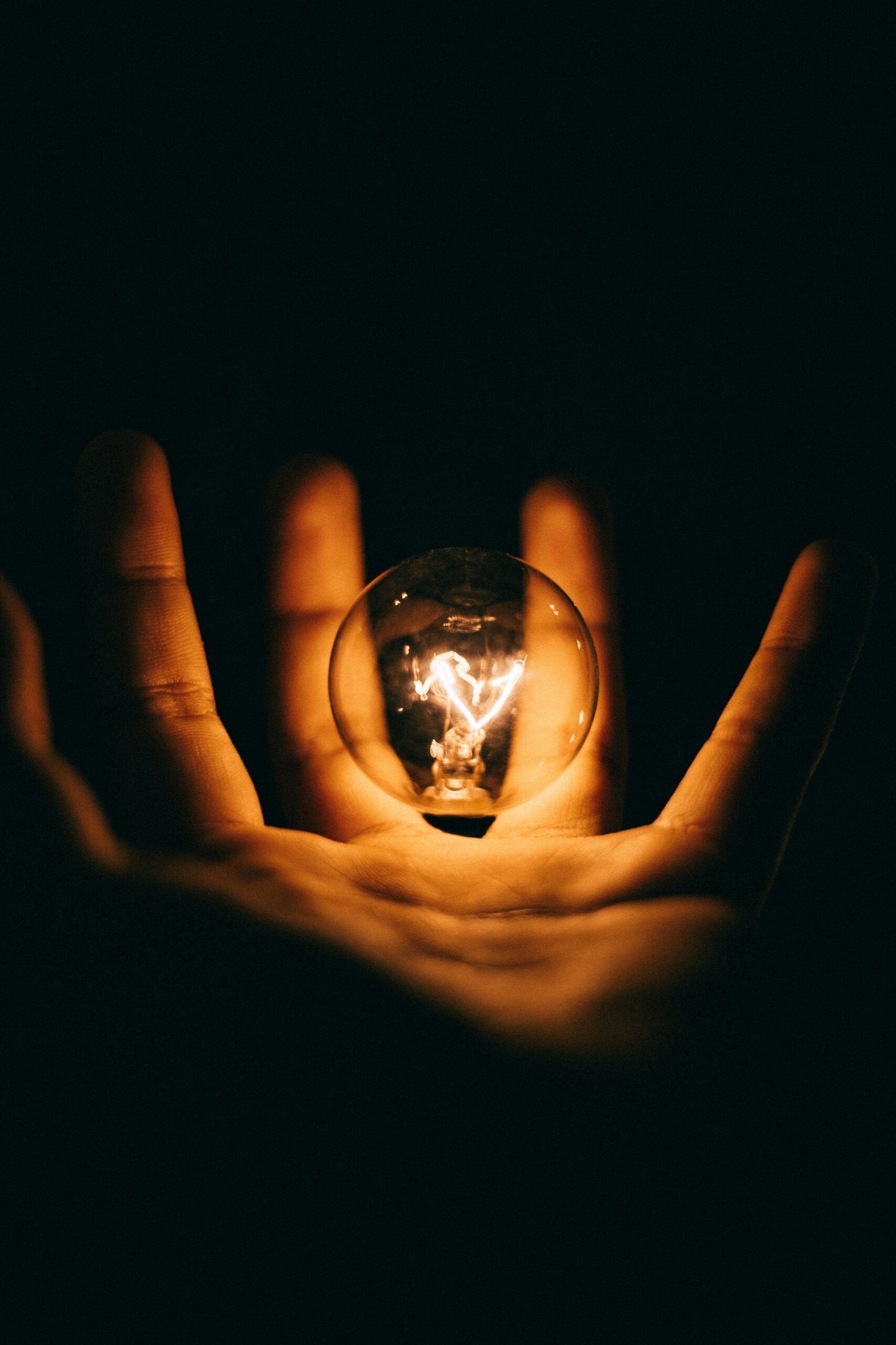 Innovative thinking idea represented by glowing light bulb held in hand for creativity and brainpower concept.