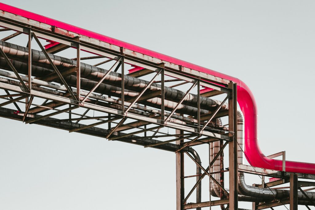 martin-adams-a_PDPUPuNZ8-unsplash | mindboost. Pipe infrastructure with a prominent pink piping, showcasing industrial elements against a clear sky. Often representing engineering, manufacturing, or industrial concepts relevant for educational content on technical topics.
