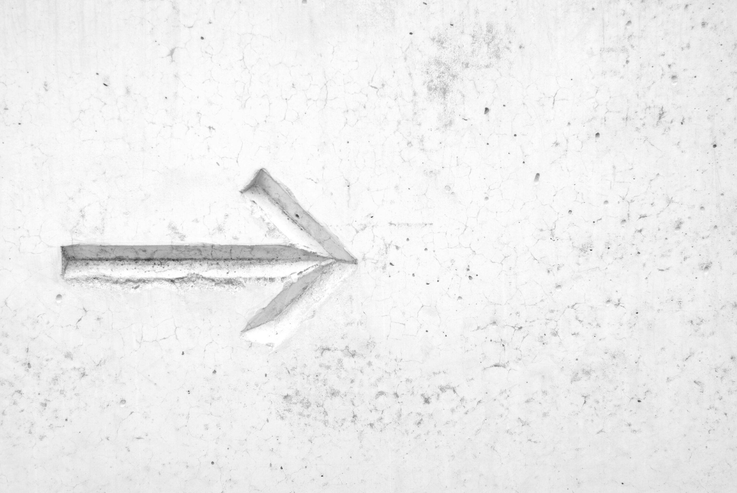 Arrow pointing right on a textured white wall, symbolising direction or progress in learning and personal development, suitable for educational or motivational content on mindboost learning platform.