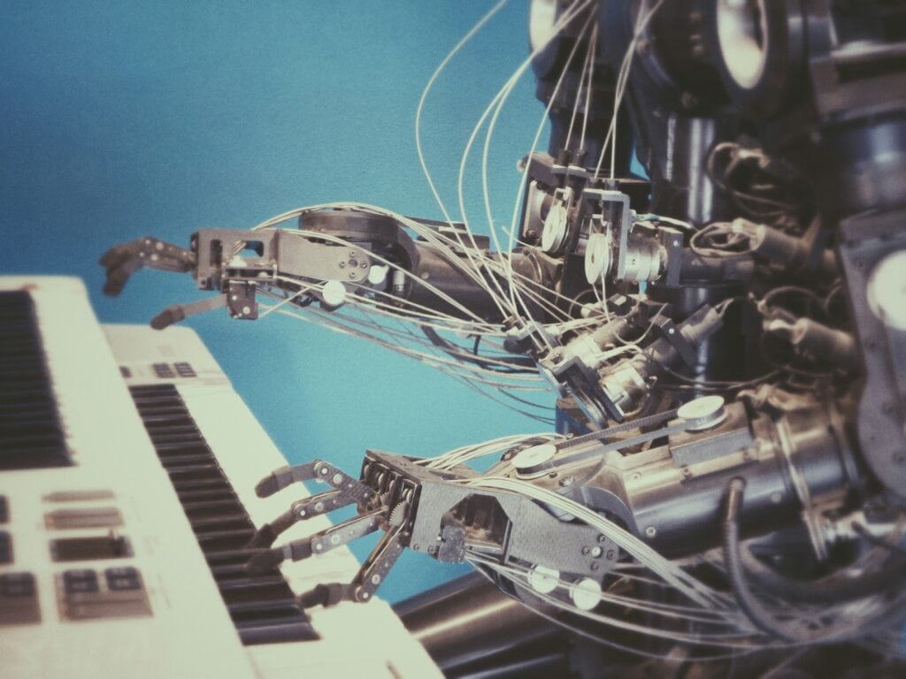 possessed-photography-U3sOwViXhkY-unsplash | mindboost. Robotic arm playing a keyboard, illustrating the connection between artificial intelligence, robotics, and music technology.