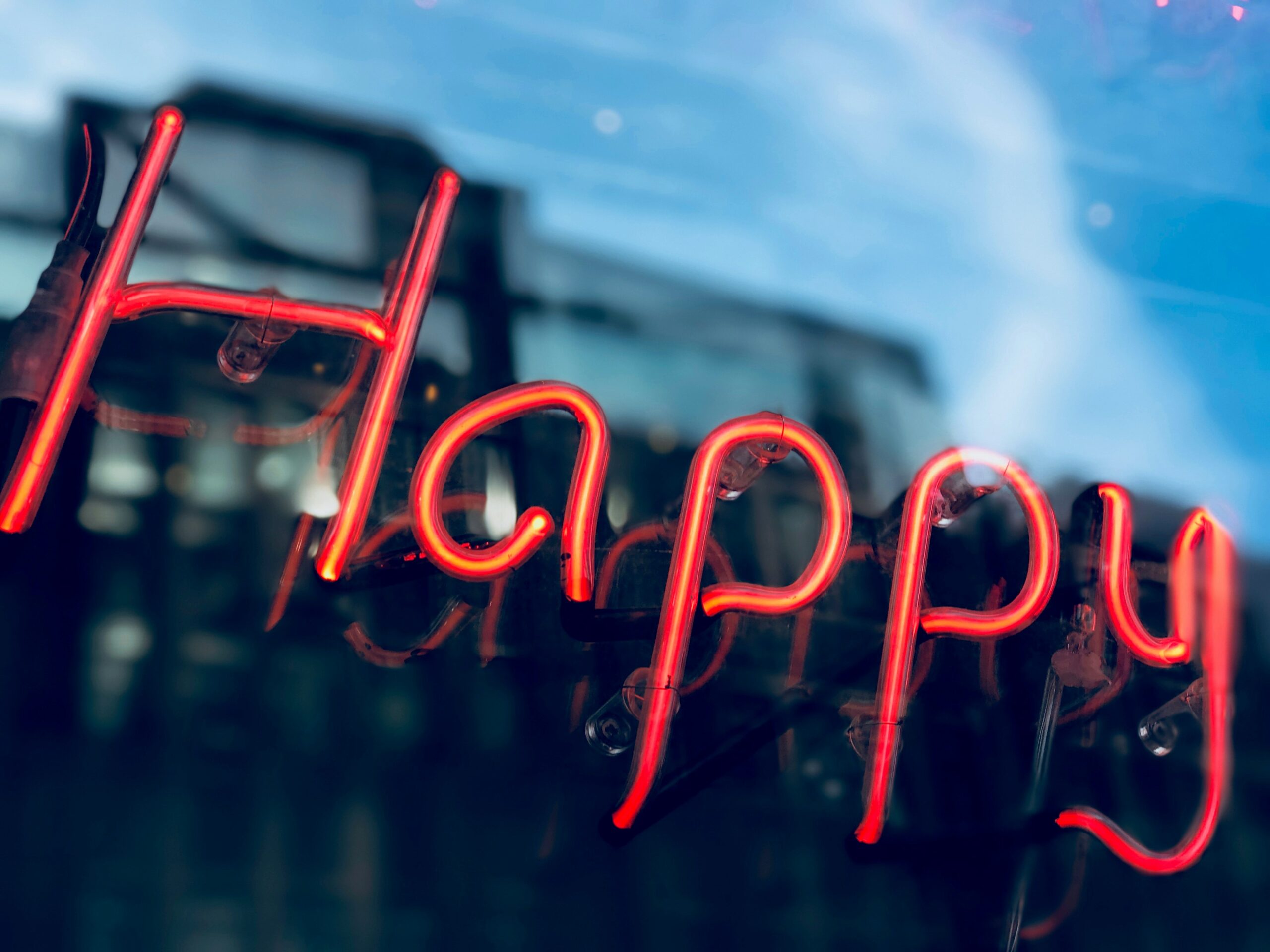 Neon "Happy" sign outside a building, vibrant red glow, contemporary city atmosphere, modern design.