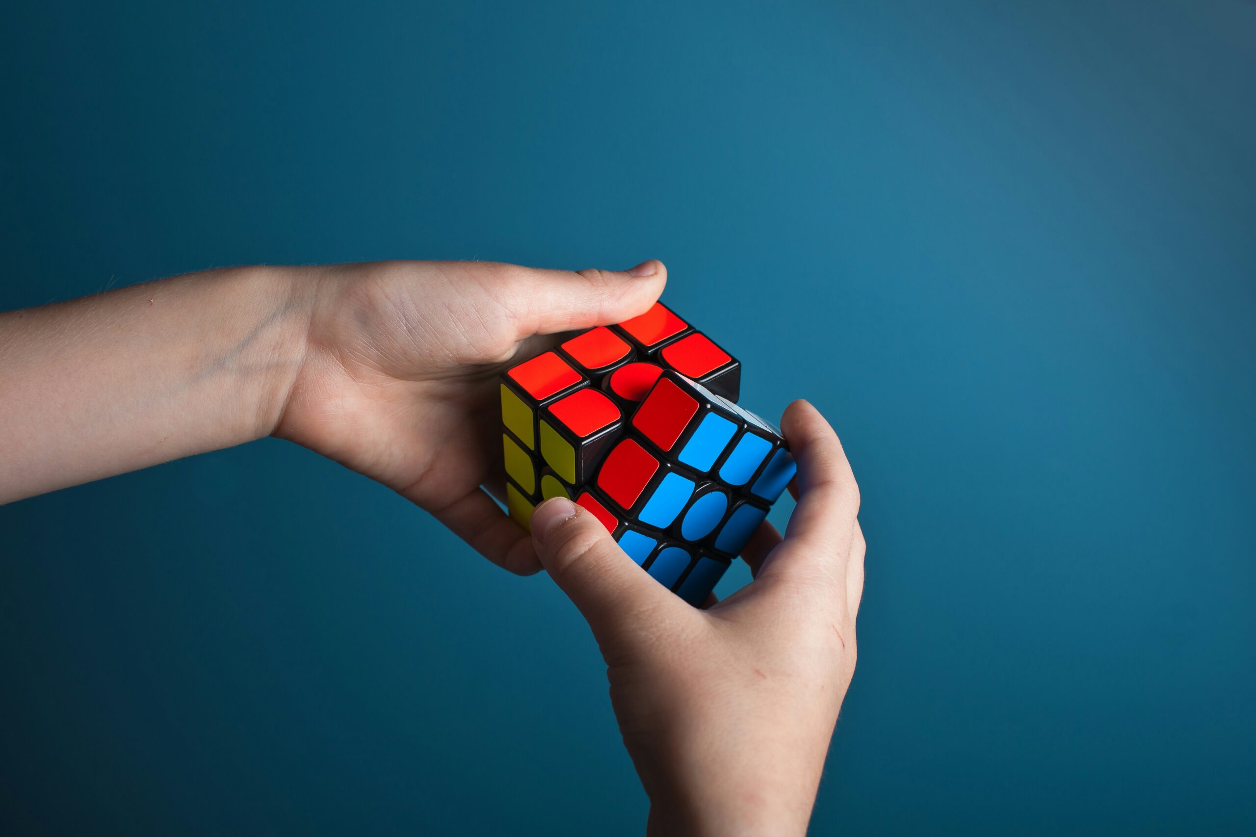A person solving a colourful Rubik’s Cube, representing problem-solving and cognitive skills enhancement. Perfect for educational and brain development articles, focusing on learning, mental agility, and memory improvement.