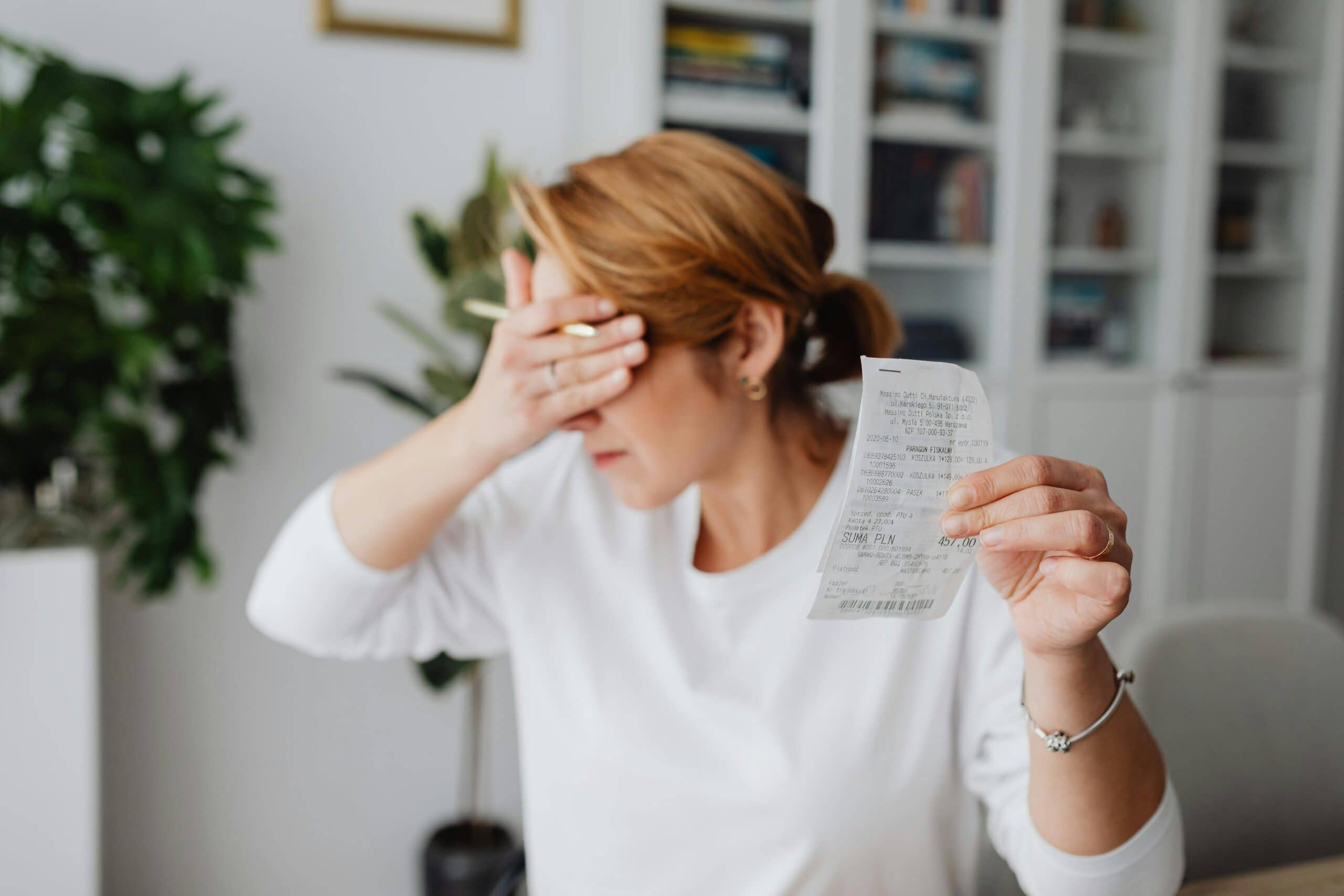 Frustrated woman holding a receipt and covering her face, representing workplace stress and challenges in proving L&D ROI to leadership.